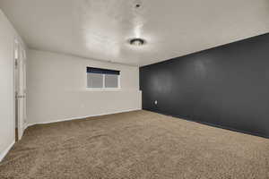 Carpeted empty room featuring a textured ceiling and baseboards