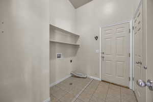 Laundry room with hookup for an electric dryer, washer hookup, light tile patterned floors, and a towering ceiling
