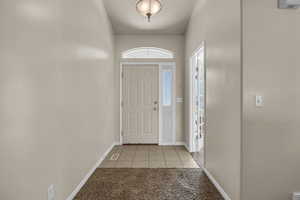 Foyer entrance featuring light tile patterned flooring and light colored carpet