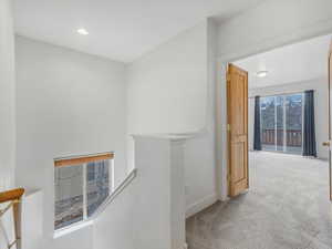 Hallway featuring an upstairs landing, carpet flooring, and recessed lighting