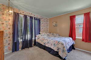 Carpeted bedroom featuring baseboards and wallpapered walls