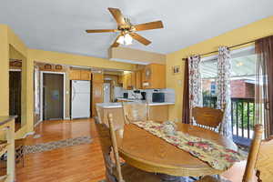 Dining room with light wood-style floors, ceiling fan, and arched walkways