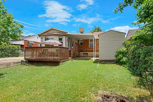 Rear view of property with a deck and brick siding