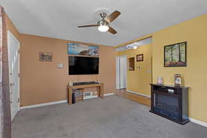 Living room with a ceiling fan, a textured ceiling, and carpet flooring