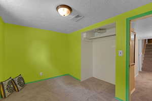 Unfurnished bedroom with a textured ceiling, carpet flooring, and a closet