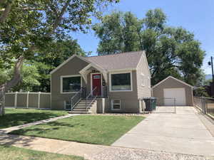 View of front facade featuring a garage, an outbuilding, driveway, and a shingled roof