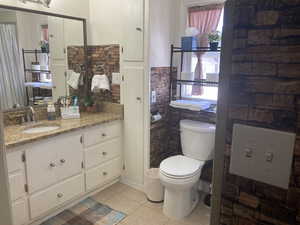 Bathroom with tile patterned flooring, vanity, and a wainscoted wall