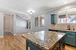 Kitchen with crown molding, backsplash, lofted ceiling, light stone countertops, and green cabinetry
