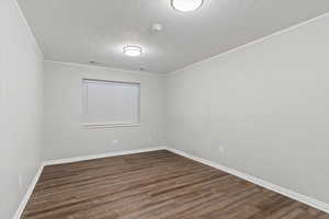 Empty room with a textured ceiling, dark wood-style flooring, and a smoke detector