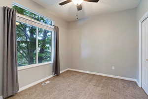 Carpeted spare room featuring a ceiling fan and baseboards