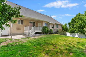 Back of house featuring stucco siding, a shingled roof, a patio, and a water view