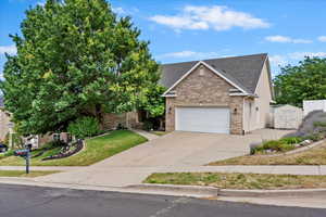 View of front of property with a shingled roof, brick siding, driveway, a front yard, and a garage