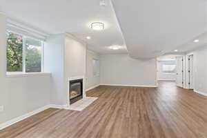 Unfurnished living room featuring wood finished floors, a tile fireplace, plenty of natural light, recessed lighting, and a textured ceiling