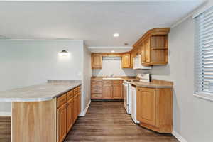 Kitchen with white appliances, a peninsula, dark wood-style flooring, recessed lighting, and light countertops