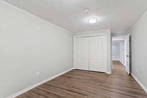 Unfurnished bedroom with a textured ceiling, wood finished floors, and a closet