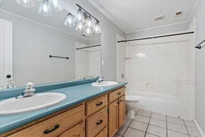 Full bathroom with double vanity, shower / bath combination, and tile patterned floors