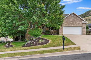 Obstructed view of property with driveway, brick siding, a front lawn, and an attached garage
