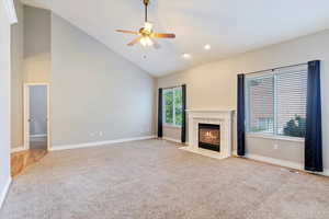 Unfurnished living room featuring carpet flooring, ceiling fan, high vaulted ceiling, a tiled fireplace, and recessed lighting