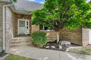 Property entrance featuring a shingled roof and brick siding