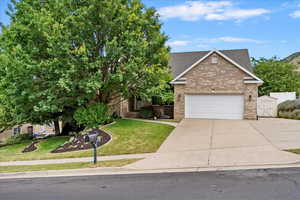View of front of property with brick siding, driveway, a front yard, a shingled roof, and an attached garage