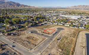 Aerial view of property and surrounding area with a mountain backdrop, property boundaries highlighted, and nearby suburban area