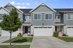 Multi unit property featuring stone siding, concrete driveway, and stucco siding