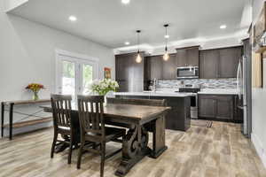 Kitchen featuring stainless steel appliances, dark brown cabinetry, light wood-type flooring, recessed lighting, and backsplash