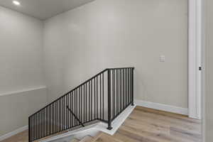 Staircase with wood finished floors and recessed lighting