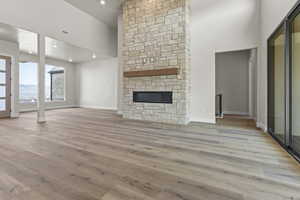 Unfurnished living room featuring a high ceiling, light wood finished floors, and a fireplace