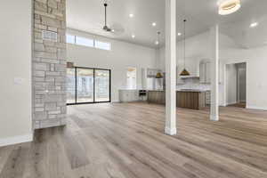 Unfurnished living room with high vaulted ceiling, a ceiling fan, light wood-type flooring, and recessed lighting