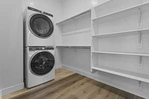 Laundry area featuring stacked washer and clothes dryer and wood finished floors