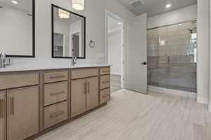 Bathroom featuring double vanity, a shower stall, and recessed lighting