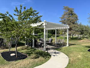View of green lawn with a pergola and a patio area