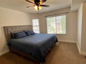 Carpeted bedroom featuring a textured ceiling and ceiling fan