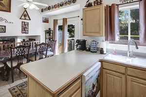 Kitchen with light brown cabinets, white dishwasher, ceiling fan, light countertops, and light tile patterned floors