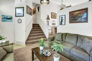 Carpeted living room featuring stairway and tile patterned flooring
