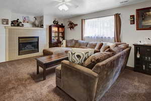 Carpeted living room featuring ceiling fan and a fireplace