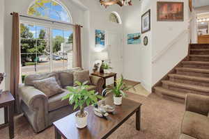 Living room featuring light carpet, stairs, and a high ceiling
