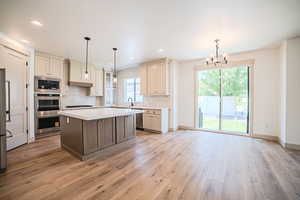 Kitchen featuring a chandelier, decorative backsplash, light countertops, light wood-style flooring, and recessed lighting