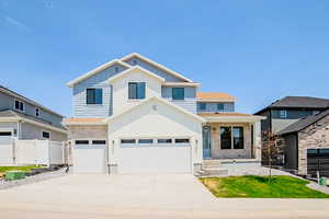 View of front of house featuring board and batten siding, concrete driveway, stone siding, a porch, and a shingled roof