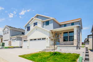 View of front of house featuring board and batten siding, a porch, stone siding, driveway, and an attached garage