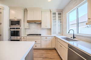 Kitchen with appliances with stainless steel finishes, light wood-style floors, light countertops, tasteful backsplash, and recessed lighting