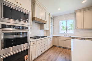 Kitchen with stainless steel appliances, light countertops, light wood finished floors, backsplash, and recessed lighting