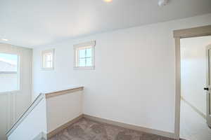 Carpeted spare room featuring a smoke detector and baseboards
