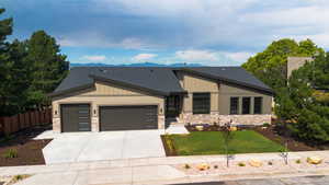 View of front of property featuring stone siding, a garage, concrete driveway, and a shingled roof