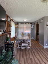 Dining area with wood finished floors, a textured ceiling, and a tile fireplace