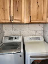 Laundry area featuring washing machine and clothes dryer and cabinet space