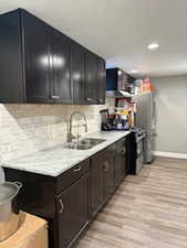 Kitchen with light wood-type flooring, light countertops, backsplash, recessed lighting, and ventilation hood