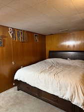 Carpeted bedroom with wood walls