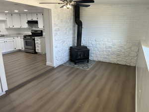 Kitchen featuring gas range, under cabinet range hood, a ceiling fan, white cabinetry, and dark wood-type flooring